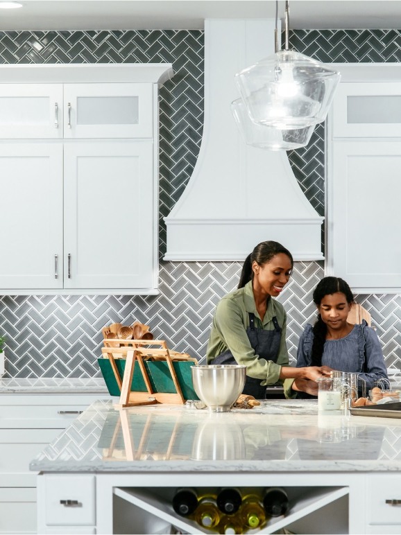 A kitchen using off-white Shaker cabinetry and barstools in front of an island.